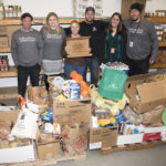 Randolph Food Shelf’s Jo Busha and Chimney Savers Co-owner Paul Bianco surrounded by Gifford staff with collected food donations.